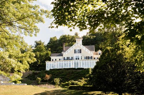 una grande casa bianca su una collina con alberi di Inn at Taughannock Falls a Ithaca