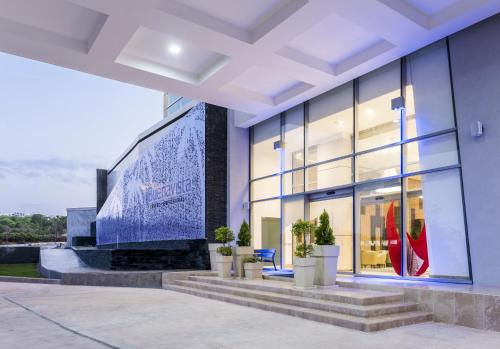 a building with a large window and potted plants at Holiday Inn Express - Barranquilla Buenavista by IHG in Barranquilla