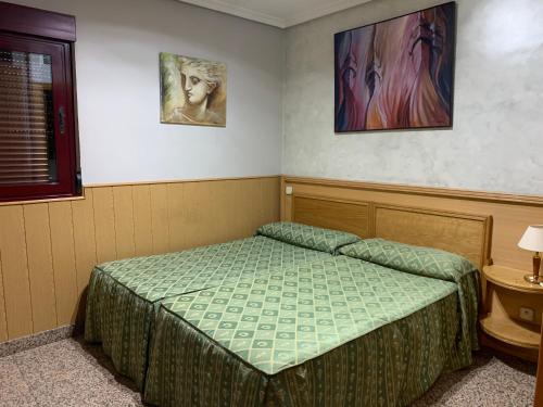 サン・セバスティアン・デ・ロス・レイエスにあるHostal Juan XXIIIのベッドと壁に絵が飾られた寝室