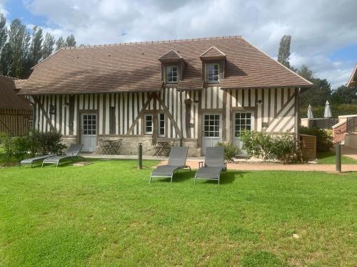 a house with chairs in the grass in front of it at Les Manoirs des Portes de Deauville - Small Luxury Hotel Of The World in Deauville