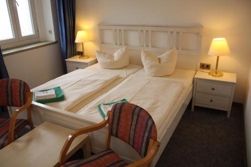 een slaapkamer met een groot wit bed en 2 stoelen bij Ferienstudio in Kurort Oberwiesenthal