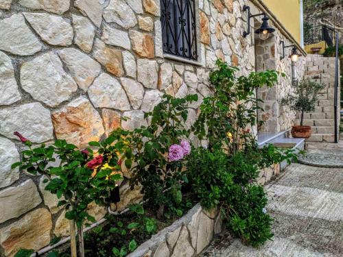 un muro di pietra con fiori e piante sopra di Meltemaki a Mouzákion