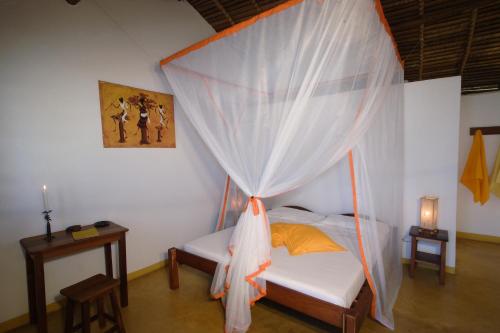 a bedroom with a bed with a mosquito net at Sambatra Bed and Breakfast in Ambaro