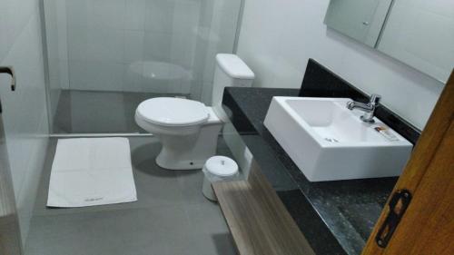 a bathroom with a white toilet and a sink at RUBBO HOTEL in São Valentim