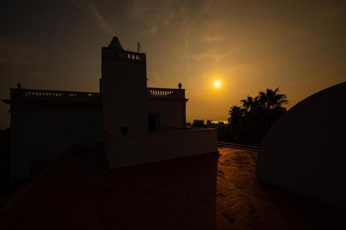 a silhouette of a building with the sunset in the background at Tancat de Codorniu in Les Cases d'Alcanar