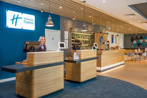 a woman is standing behind a counter in a restaurant at Holiday Inn Express - Bodmin - Victoria Junction by IHG in Bodmin