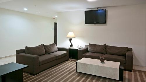 a living room with a couch and a tv on the wall at Holiday Inn Express Ciudad Del Carmen by IHG in Ciudad del Carmen