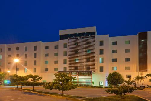 a large building with a parking lot in front of it at Holiday Inn Express Ciudad Del Carmen by IHG in Ciudad del Carmen