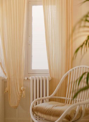 a white chair in a room with a window at Shila Athens in Athens