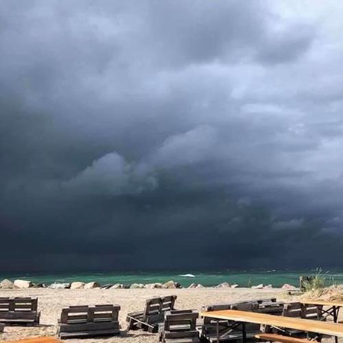 a group of lounge chairs on a beach with a threatening sky at Casablanca Hostel, hyggelig overnatning in Anholt