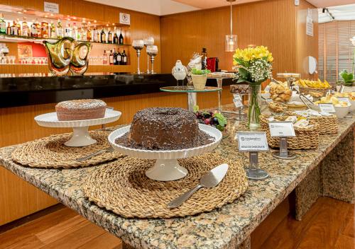 a counter with two cakes sitting on top of it at Hotel Nacional Inn Cambuí Campinas Residence in Campinas