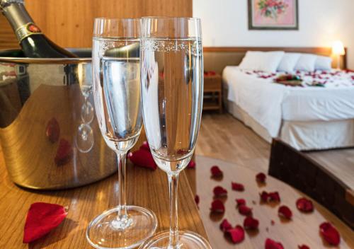 two champagne glasses sitting on a table in a bedroom at Hotel Nacional Inn Cambuí Campinas Residence in Campinas