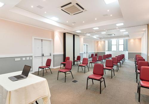 a conference room with red chairs and a laptop on a table at Hotel Nacional Inn Cambuí Campinas Residence in Campinas
