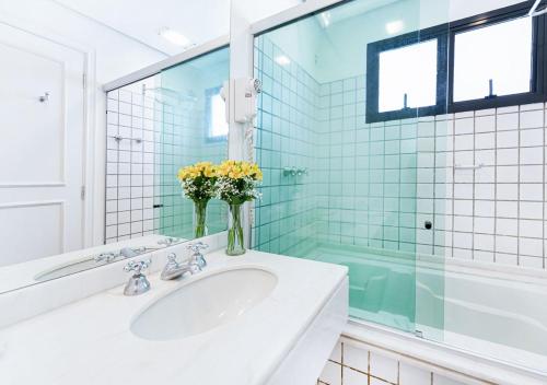 a bathroom with a sink and a vase of flowers at Hotel Nacional Inn Cambuí Campinas Residence in Campinas