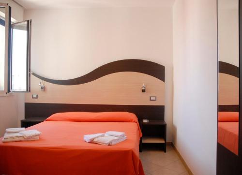 a bedroom with two beds with orange sheets and towels at Tropicana Residence in Lido degli Estensi