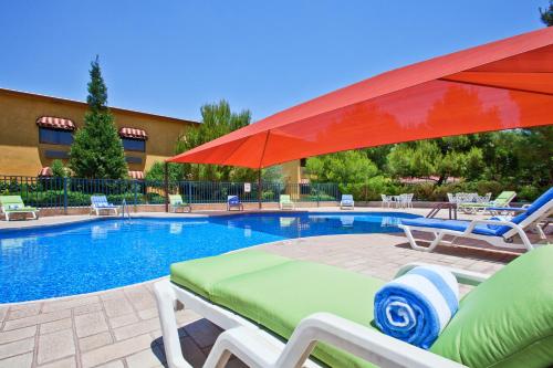a swimming pool with chairs and a red umbrella at Holiday Inn Express Chihuahua by IHG in Chihuahua