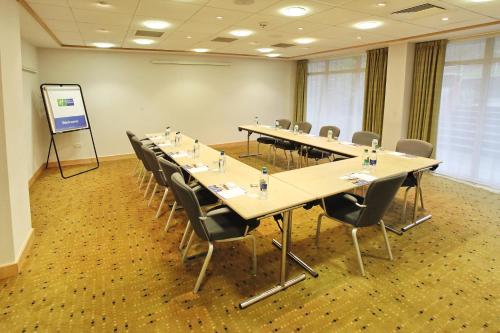 a conference room with tables and chairs and a screen at Holiday Inn Express Birmingham Redditch by IHG in Redditch