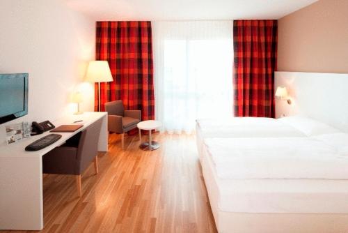 a bedroom with a bed and a desk with a computer at Hotel Arcade in Sins