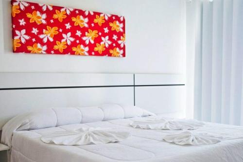 um quarto com uma cama branca e uma pintura na parede em Residencial Monte Moria em Porto Seguro