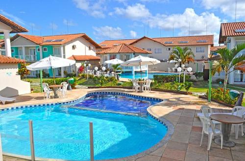 einen Pool mit Stühlen und Tischen in einem Resort in der Unterkunft Residencial Monte Moria in Porto Seguro