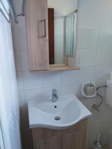 bagno con lavandino bianco e specchio di SAM'S ROOMS a Città di Corfù