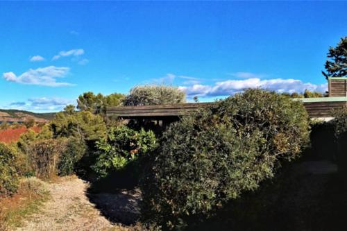 a bridge over a river with bushes in a field at Studio 22 m2, terrasse vue montagne, dans propriété face au Lac du Salagou in Liausson