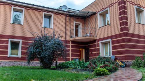 a red house with a balcony and a yard at Arcobaleno Home in Kyiv
