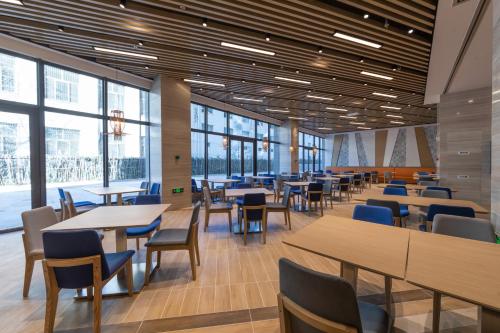 a dining room with tables and chairs and windows at Holiday Inn Express Kaifeng City Center, an IHG Hotel in Kaifeng