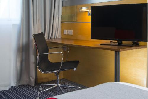 a desk with a chair and a television on it at Holiday Inn Express London - Epsom Downs by IHG in Epsom