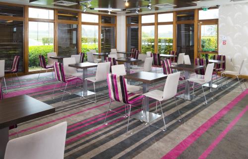 a dining room with tables and chairs and windows at Holiday Inn Express London - Epsom Downs by IHG in Epsom