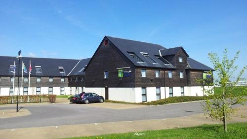 a large building with a car parked in a parking lot at Holiday Inn Express London - Epsom Downs by IHG in Epsom