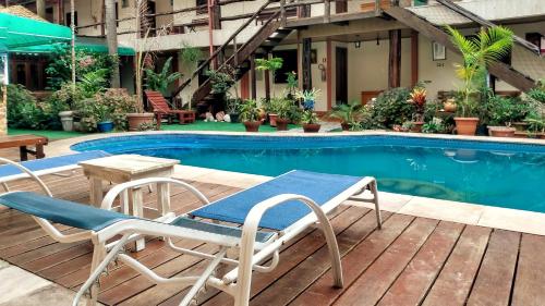 einen Pool mit 2 Stühlen und einem Tisch neben einem Tisch in der Unterkunft hotel le Massilia in Belém