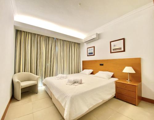 a bedroom with a bed and a chair and a window at Sea Gardens - Alvaflor - Vilamoura in Vilamoura