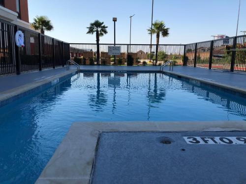an empty swimming pool with palm trees and a fence at Holiday Inn Express Hillsboro I-35 by IHG in Hillsboro