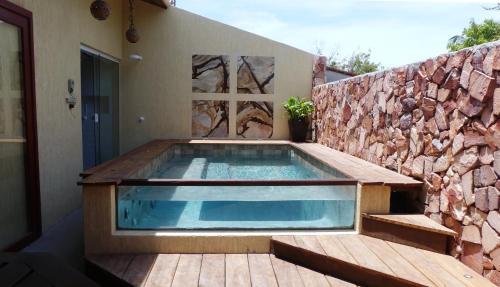 a swimming pool in front of a stone wall at Pousada O Refúgio in Jericoacoara