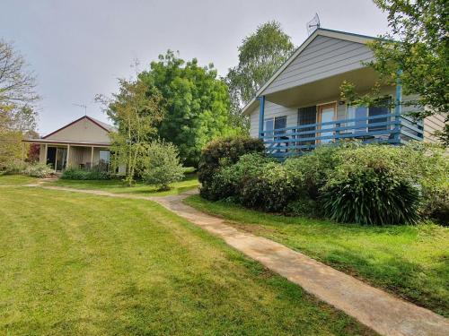 a blue house with a dirt road in front of it at Neerim Country Cottages in Neerim South