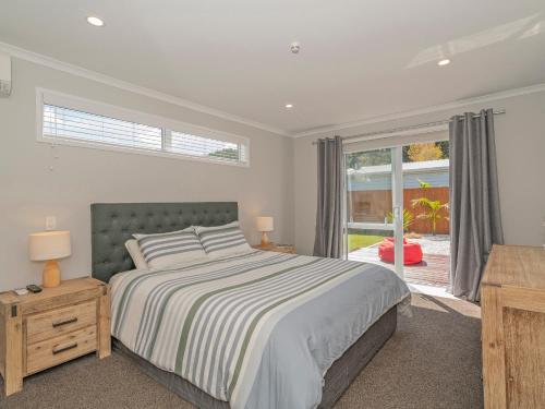 a bedroom with a bed and a large window at Modern Beach Pad - Whitianga Holiday Home in Whitianga