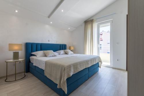 sypialnia z niebieskim łóżkiem i oknem w obiekcie Apartments Prestige w mieście Kaštela