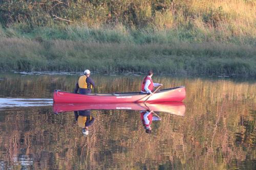 two men are rowing a red canoe in the water at Deer Lake Horizon Hotel in Deer Lake