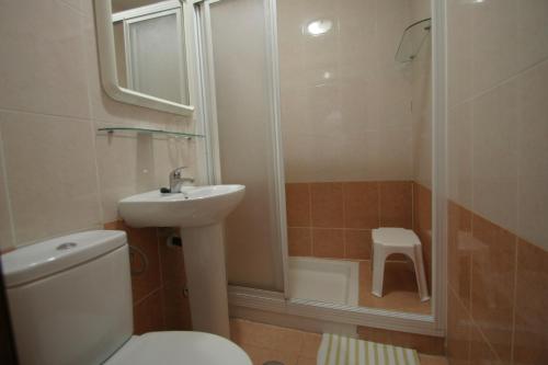 Un baño con inodoro, lavabo y ducha. en Pension el Portillo, en Córdoba