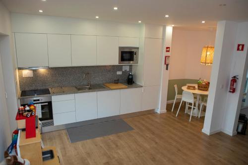 a kitchen with white cabinets and a table in it at Casa do Arco in Amarante