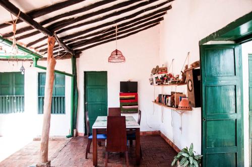 a dining room with a table and green doors at Nacuma Garden Hostel - Casa Nacuma in Barichara