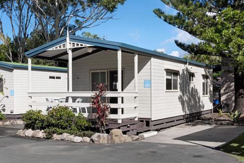 a small white house with a blue roof at Discovery Parks - Emerald Beach in Emerald Beach