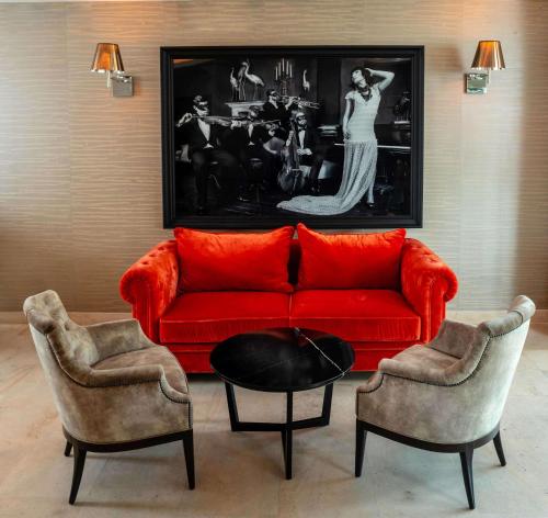 a living room with a red couch and two chairs at Best Western Plus Le Lavarin in Avignon