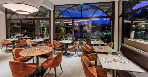 a restaurant with tables and chairs and large windows at Best Western Plus Le Lavarin in Avignon