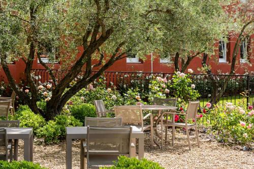 a group of tables and chairs in a garden at Best Western Plus Le Lavarin in Avignon