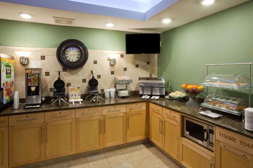 a kitchen with wooden cabinets and a clock on the wall at AmericInn by Wyndham Hartford SD in Hartford