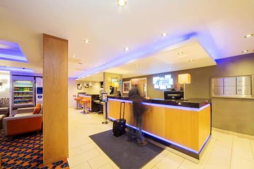 a man standing at a bar in a hotel lobby at Holiday Inn Express Edinburgh – Royal Mile by IHG in Edinburgh