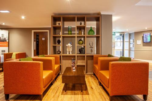 uma sala de espera com cadeiras laranja e uma mesa em Holiday Inn Express Edinburgh Airport, an IHG Hotel em Ingliston