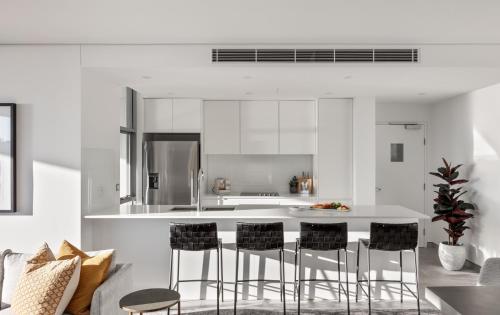 a kitchen with a white island with black bar stools at Argo Apartments in Wollongong